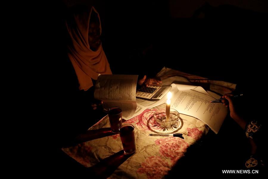 الصورة: طالبة سودانية تستذكر دروسها على ضوء شمعة عقب انقطاع التيار الكهربي في السودان 