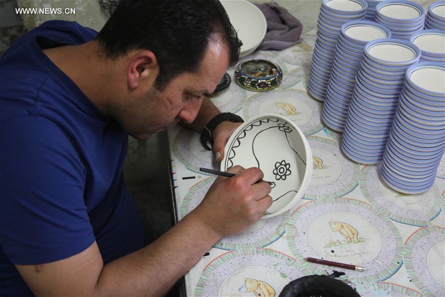 الصورة: فلسطينيون يرسمون على مادة السيراميك في مصنع التميمي بالضفة الغربية
