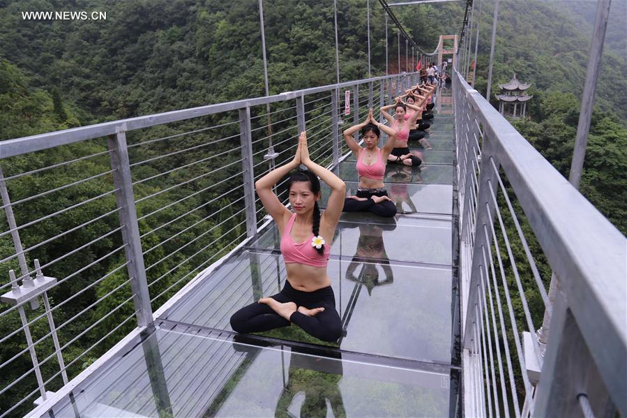 الصورة : هواة اليوغا يتدربون على جسر زجاجي معلق في وسط الصين