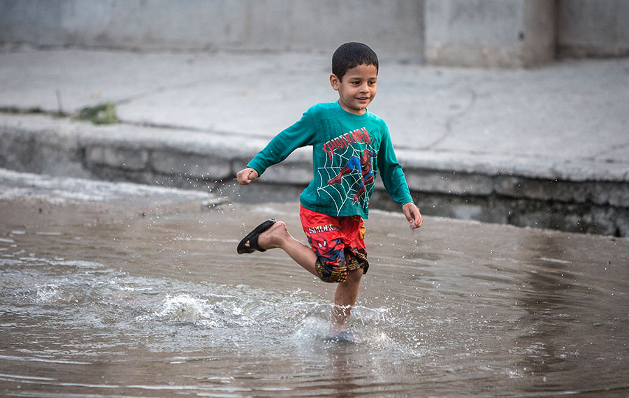 أطفال يهربون إلى المياه من موجه الطقس الحار في طهران