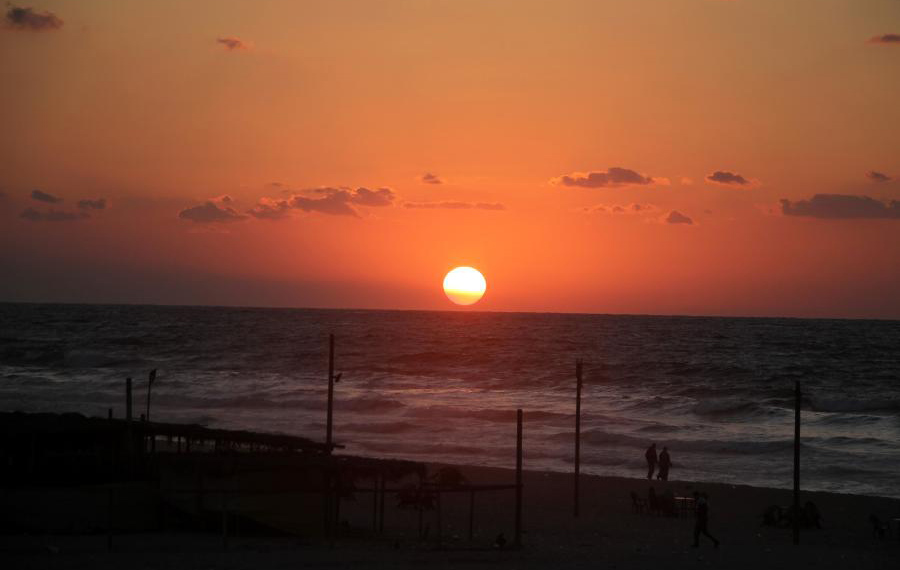 فلسطينيون يستمتعون بغروب الشمس على الشاطئ في مدينة غزة