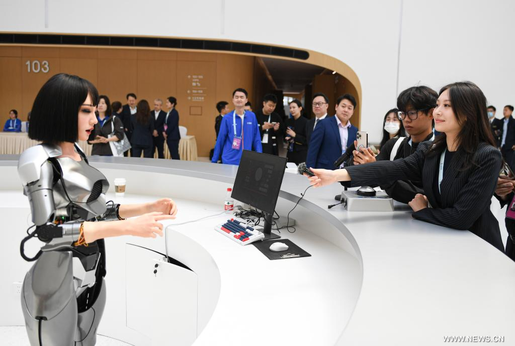 في هذه الصورة الملتقطة يوم 24 أبريل 2024، صحفيون  مع روبوت بشري في مركز تشونغقوانتسون الدولي للابتكار، المكان الجديد لاستضافة منتدى تشونغقوانتسون، في العاصمة الصينية بكين.